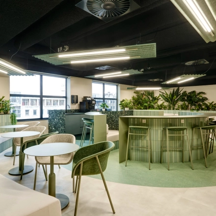 Modern office space with green-themed furnishings at Weena 335, Rotterdam Center, available for rent. Includes seating areas and plants, ideal for informal meetings.