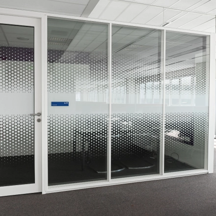 Modern office space to rent at Weena 70, Rotterdam Center, featuring a glass-walled meeting room with geometric patterns offering natural light.