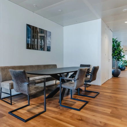 Furnished interior workspace at Weena 788, Rotterdam Center, featuring a sleek wooden table and modern chairs, perfect for rent office space needs.