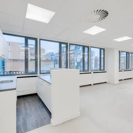 Modern office space for rent at Westblaak 109, Rotterdam Center, featuring large windows and a kitchenette with a sink.