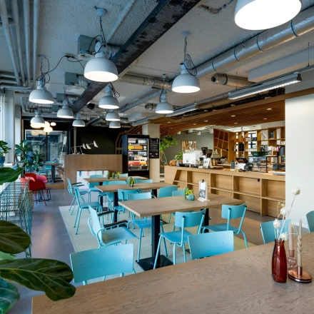 Bright office space at Westblaak 180, Rotterdam Center, with modern furnishings and greenery. Ideal for office space rental with spacious tables and vibrant decor.