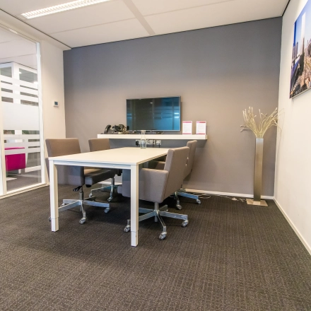 Furnished office space rental at Weena-Zuid 130, Rotterdam Central Station with meeting table, chairs, screen, and modern decor.