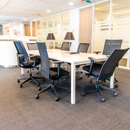 Modern office space rental at Weena-Zuid 130, Rotterdam Central Station featuring a conference table with chairs, ideal for meetings.