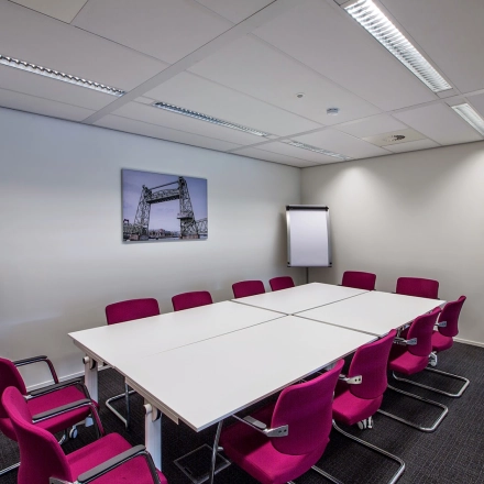 Furnished conference room at Weena-Zuid 130, Rotterdam Central Station, available for office space rental with magenta chairs and white tables.