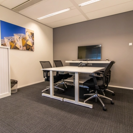 Modern office to rent in Rotterdam Central Station with a meeting table, chairs, and a mounted TV, ideal for office space rental at Weena-Zuid 130.