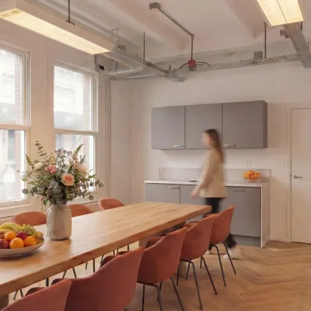 Bright office space at Lloydstraat 5 in Rotterdam Delfshaven featuring a long table, chairs, and a kitchenette.