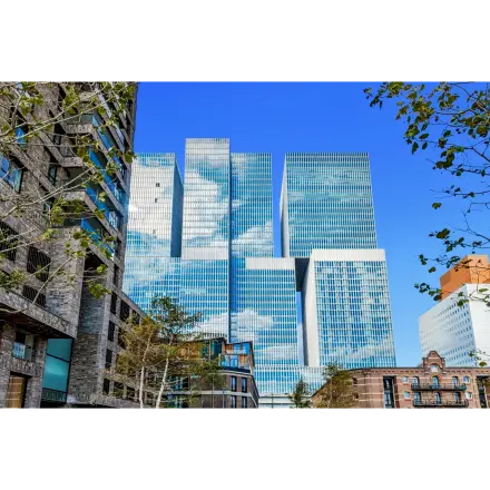 Exterior view of a modern office building located at Wilhelminakade 173, Rotterdam Kop van Zuid, ideal for office space rental with glass facade reflecting the blue sky.