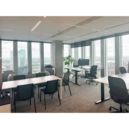 Modern office space at Wilhelminakade 173, Rotterdam Kop van Zuid, featuring large windows and multiple desks, ideal for workspaces. A perfect spot for office space rental with a panoramic city view.
