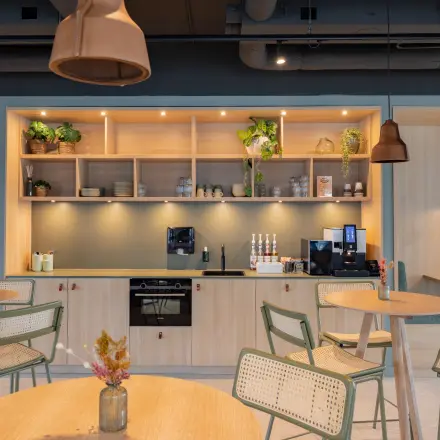Furnished office space with modern tables and greenery, available for office space rental at Wilhelminaplein 1-40 in Rotterdam Kop van Zuid.