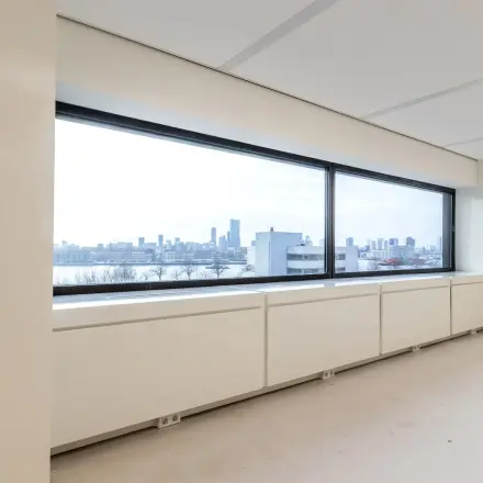 Interior view of an unfurnished office space with large windows offering a panoramic view of Rotterdam skyline at Oostmaaslaan 71.