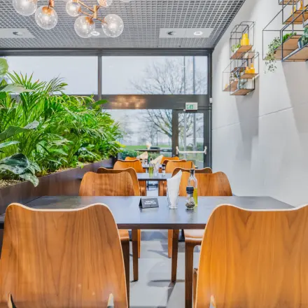 Modern furnished lounge area with tables and plants at an office space rental on Oostmaaslaan 71, Rotterdam Kralingen.