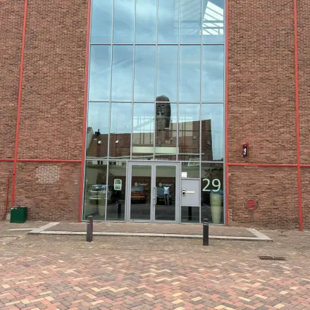 Exterior view of the office building at Scheepsbouwweg 29, Rotterdam Waalhaven, showcasing a modern glass entrance suitable for those seeking office space rental.
