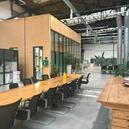 Spacious industrial-style interior at Scheepsbouwweg 29, Rotterdam Waalhaven, featuring a long wooden table and chairs suitable for collaborative work. Ideal for office space rental.