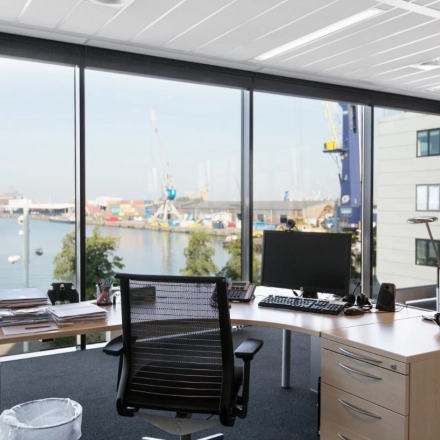Bright office space at Waalhaven O.z. 83, Rotterdam Waalhaven, featuring a modern desk setup with a scenic harbor view, ideal for office space rental.