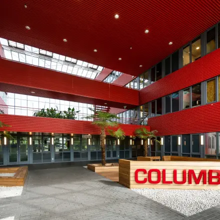 Modern office entrance with red and grey architectural design and skylight in Schiphol Airport for office space rental.
