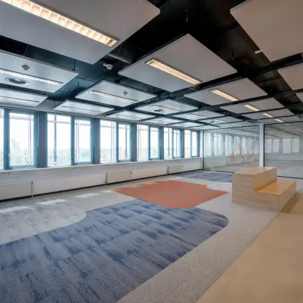 Spacious office area with modern lighting and large windows offering a panoramic view, ideal for office space rental at Schiphol Airport.