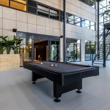 Modern office space at Beechavenue 54-100, Schiphol Rijk, featuring a pool table and seating area for rent. Light-filled interior with large windows, perfect for office space rental.