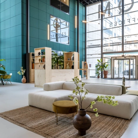Spacious office lobby with modern furnishings, plants, and large windows at Beechavenue 54-100, Schiphol Rijk. Ideal for those looking to rent office space with a bright, welcoming ambiance.