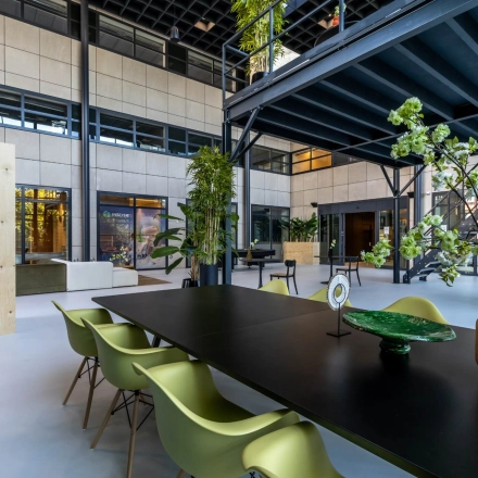 Spacious and stylish interior at Beechavenue 54-100, Schiphol Rijk, perfect for office space rental. Modern furnishings include green chairs and decorative plants, ideal for collaborative workspaces.