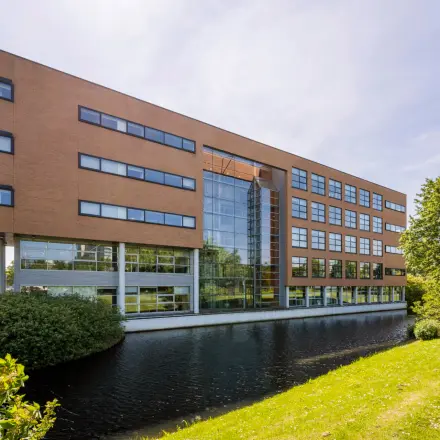 Exterior view of an office building at Boeing Avenue 1-19, Schiphol Rijk, ideal for office space rental with a modern facade next to a serene water body.