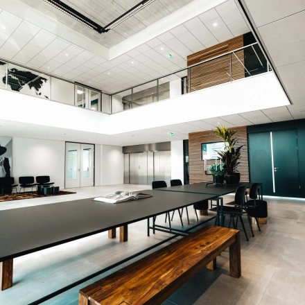 Modern office at Schiphol Rijk with a spacious meeting table and seating area, ideal for those looking to rent office space. Art decorates the walls, complementing the sleek design.