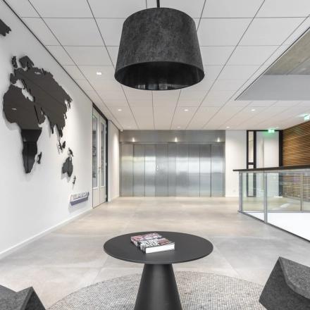 Modern office space at Tupolevlaan 81-99, Schiphol Rijk, featuring sleek seating, a world map wall decoration, and elevator access. Ideal for office space rental.