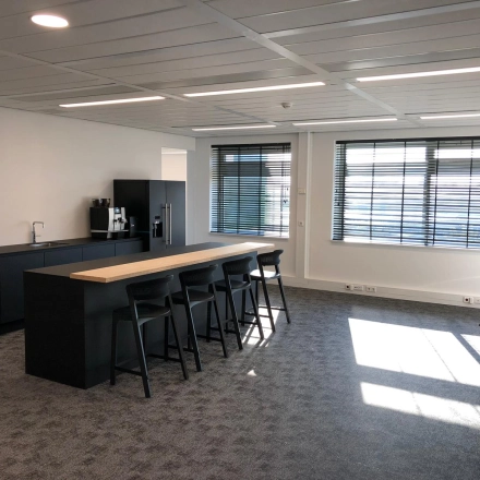 Spacious, well-lit office interior featuring a kitchenette with bar stools, perfect for office space rental in Schiphol Rijk at Tupolevlaan 81-99.