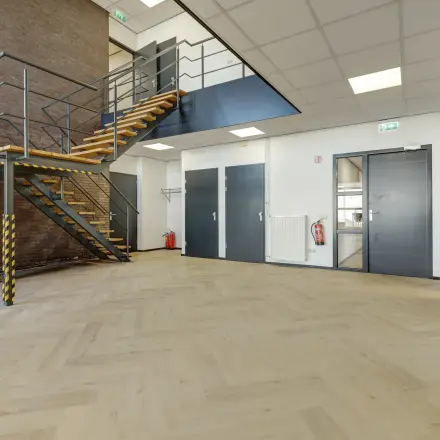 Interior view at Fischerpad 106 in Sittard showing an open floor plan with a staircase and modern design ideal for office space rental opportunities.