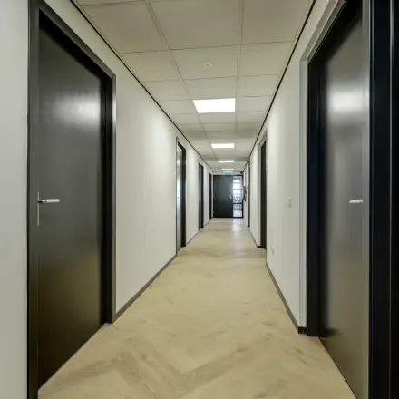 A hallway with closed doors leading to office space rental at Fischerpad 106, Sittard.