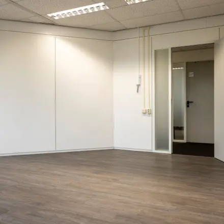 An unfurnished office space with wooden flooring and white walls, offering potential for tailored office space rental at Curieweg 9, Spijkenisse.
