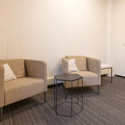 Modest office space at Curieweg 9, Spijkenisse, featuring two comfortable chairs and a small table, suitable for meetings or relaxation. Ideal for office space rental.
