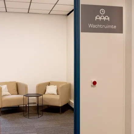 Cozy office space to rent at Curieweg 9, Spijkenisse, featuring a small waiting area with two beige armchairs and a round black table.