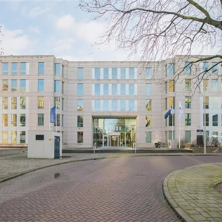 Exterior view of the Alexanderveld 5-9 office building in The Hague Center featuring a modern facade with large windows and a welcoming entrance, ideal for office space rental.