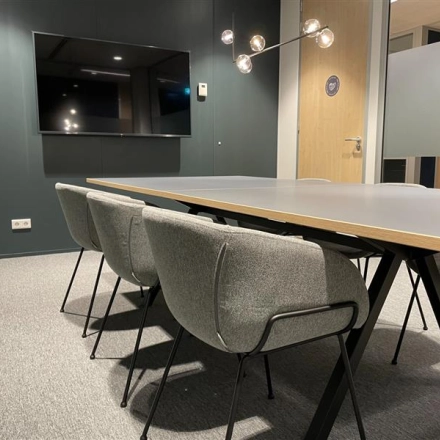Modern conference room with a sleek table, comfortable chairs, and a wall-mounted TV, suitable for office space rental in The Hague Center at Alexanderveld 5-9.