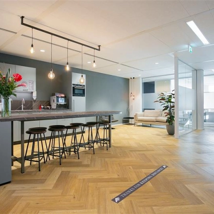 Spacious office interior at Alexanderveld 5-9 in The Hague Center, featuring a modern pantry area with counter seating and a lounge space. Ideal for office space rental with stylish furnishings and open layout.