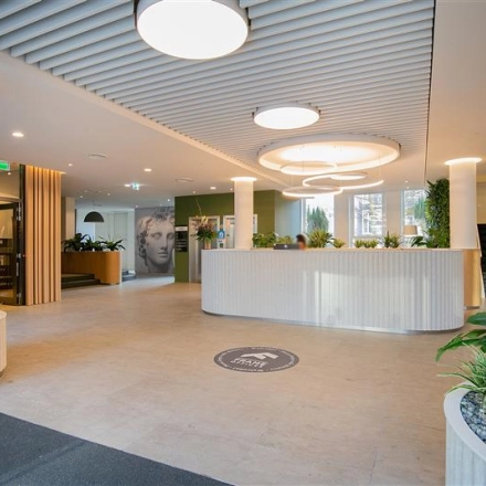 Spacious reception area at Alexanderveld 5-9, The Hague Center featuring modern lighting and greenery. Ideal for a professional office space rental.
