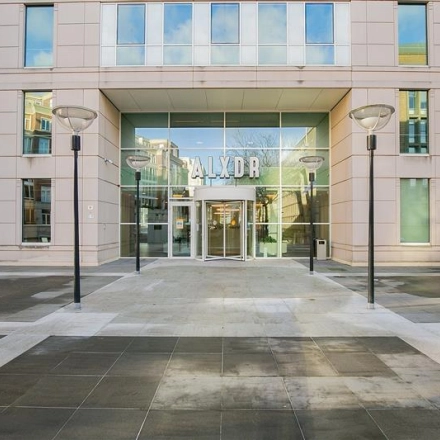 Entrance of an office building at Alexanderveld 5-9 in The Hague Center, showcasing a modern facade with large glass doors, ideal for office space rental.