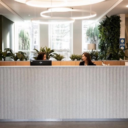Modern, inviting reception area at Alexanderveld 5-9, The Hague Center, featuring a curved front desk and greenery, ideal for office space rental.