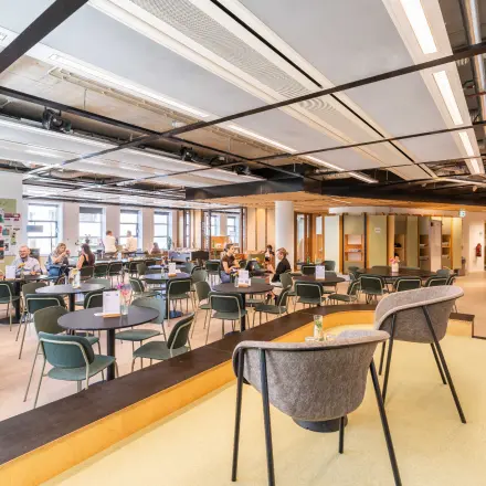 Vibrant office space in The Hague Center with modern furnishings and professionals collaborating at desks. Ideal for office space rental.