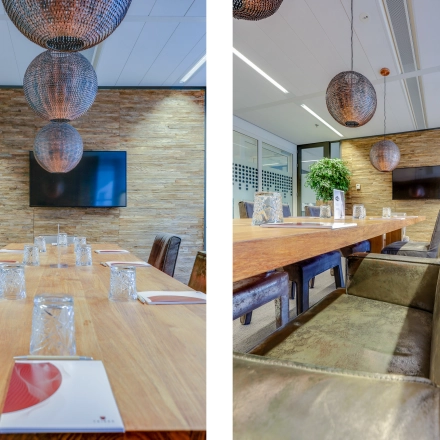 Spacious conference room at Kalvermarkt 53, The Hague Center, featuring a large wooden table, leather chairs, and decorative lighting. Ideal office space rental for meetings. TV mounted on textured wall.