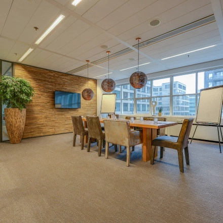 Spacious, well-lit conference room with a large wooden table and chairs, suitable for office space rental in The Hague Center.