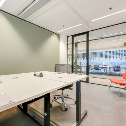 Interior view of furnished office space at Kalvermarkt 53, The Hague Center, featuring a desk, chairs, and a decorative plant. Ideal for office space rental or as an office to rent.