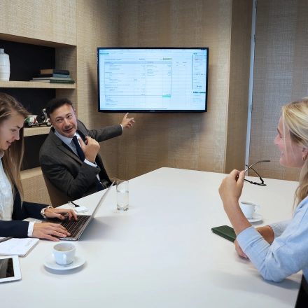 Colleagues in The Hague Center discuss project details in a modern conference room at Koninginnegracht 19. Ideal office space rental for collaborative meetings.
