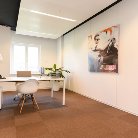 Bright office space with a large desk, modern chair, and artwork on the wall at Koninginnegracht 19, ideal for rent office space in The Hague Center.