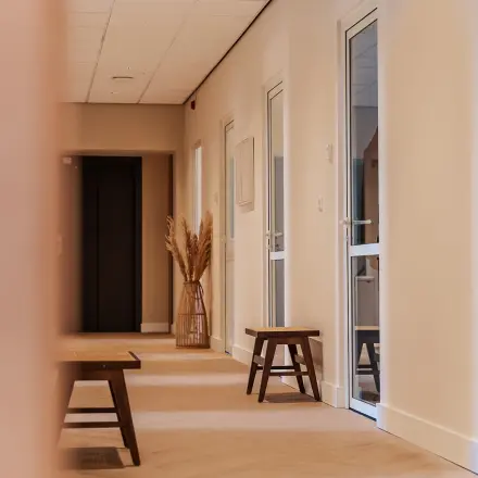 Modern office hallway at Zeestraat 100, The Hague Center, featuring wooden benches and soft lighting, ideal for office space rental.