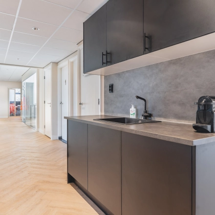 Modern kitchenette in Zeestraat 100 office space with sleek cabinets and coffee machine, perfect for office space rental in The Hague Center.