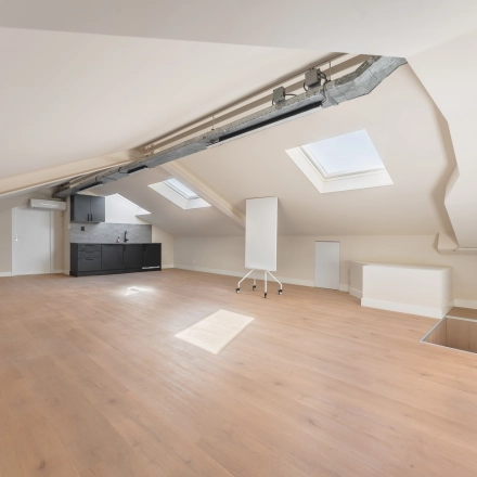 Spacious office space rental at Zeestraat 100, The Hague Center, featuring wooden flooring, skylights, and a kitchenette.