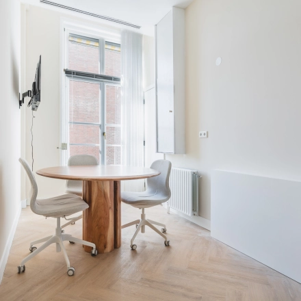 Bright office space with a round table and chairs at Zeestraat 100, The Hague Center, ideal for rental.