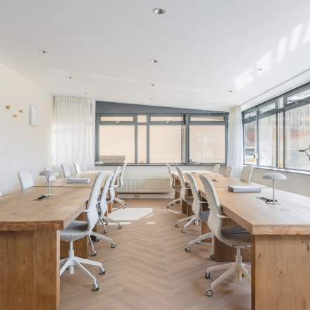 Bright office space with wooden desks and chairs, available for office space rental at Zeestraat 100 in The Hague Center.