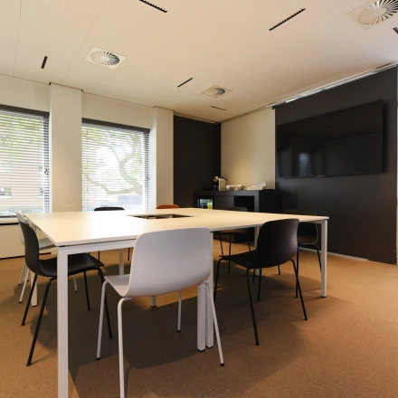 Bright office space for rent in The Hague Statenkwartier featuring a modern conference room with large windows, minimalist tables, and chairs.